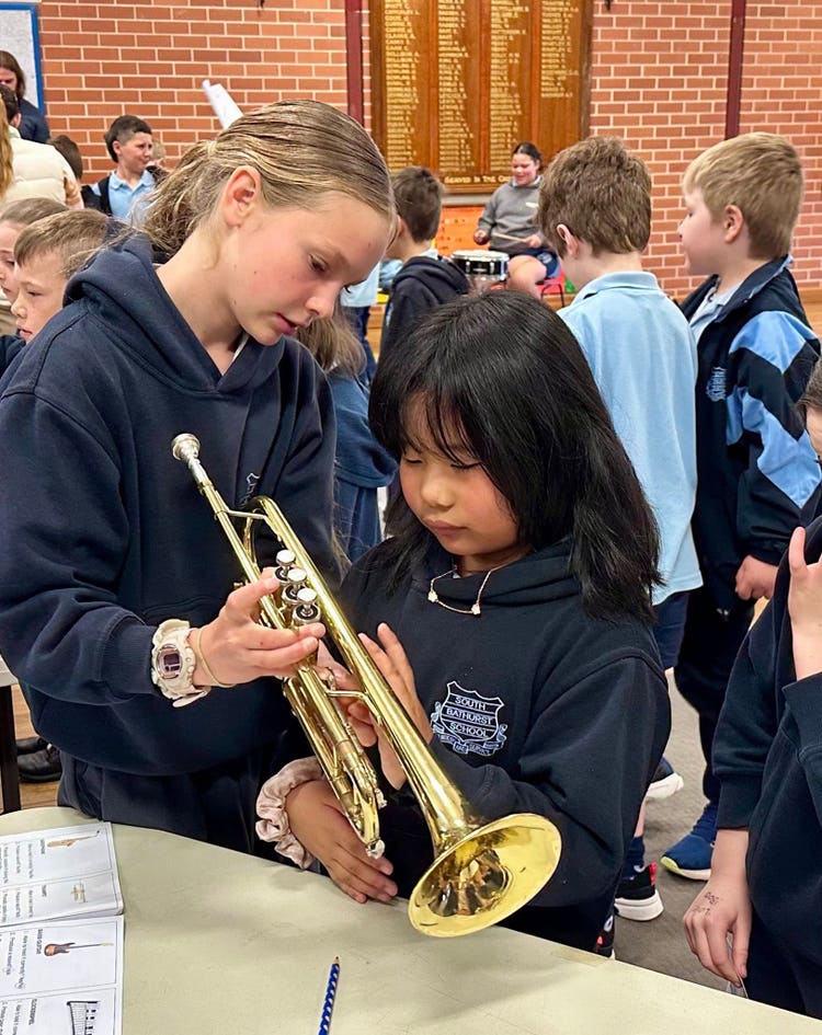 an image of 2 people, demonstrating trumpet