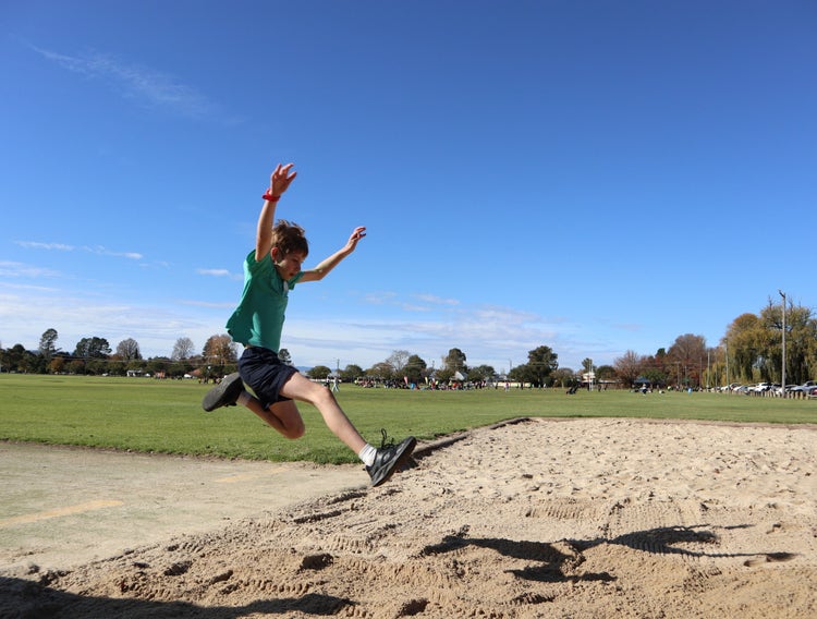 Boy jumping into long jump pit