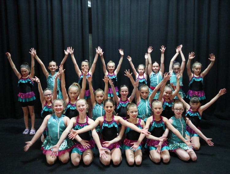 Group photo of dancers in blue and purple glittery costumes